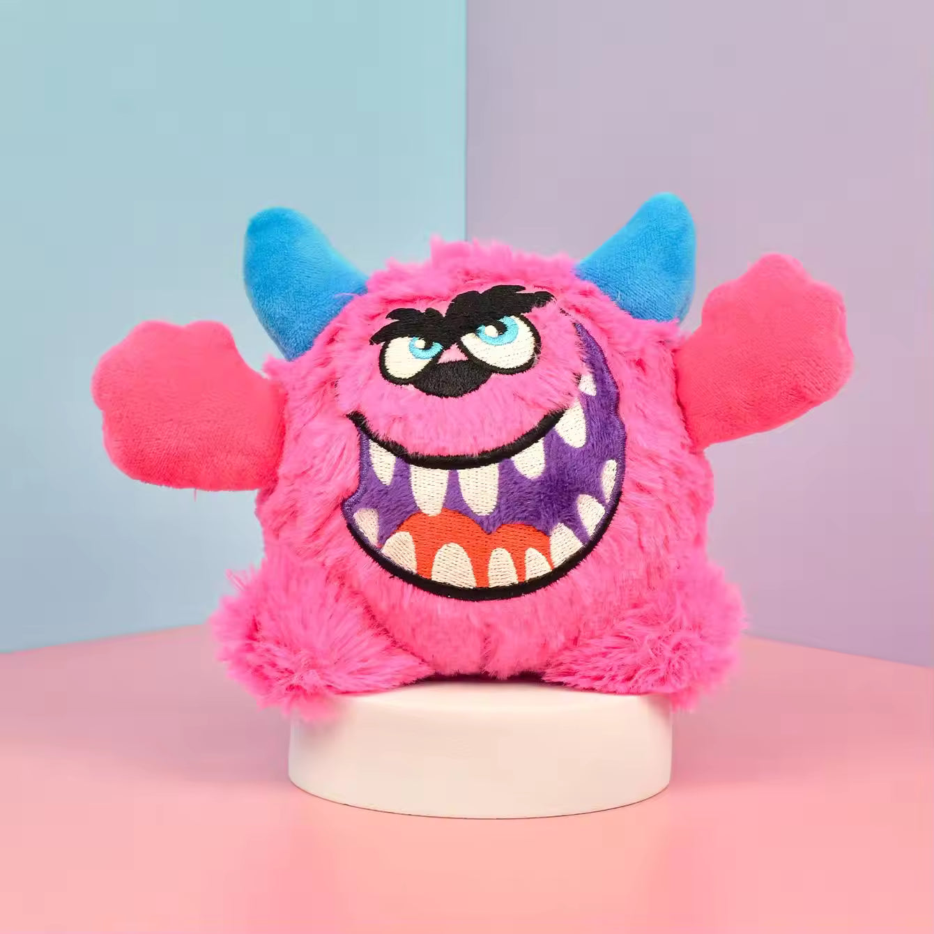 Pet Supplies Interactive Squeaky Plush Dog Toy Pink plush monster toy with blue horns on a pink and blue gradient background