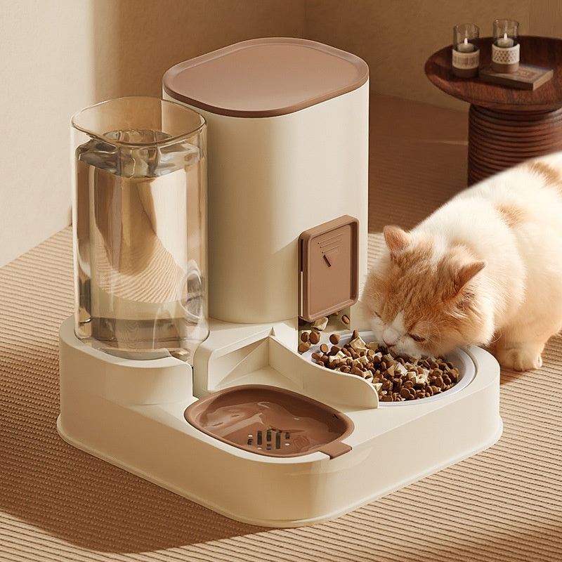 Pet Supplies Automatic Pet Feeder & Water Dispenser An automatic pet feeder with a stainless steel bowl and a clear water reservoir, in a color close to beige, with a cat eating from it.